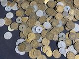 a lot of coins sitting on a table next to a measuring tape
