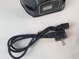 a small black object on a white surface with a cord