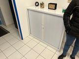une femme debout dans une salle de bains, à côté d'une armoire