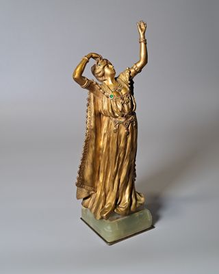 statue en or représentant une femme les bras levés vers le ciel