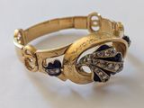 une photo en gros plan d'un bracelet en or orné de pierres bleues et blanches
