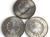 three silver coins sitting on top of each other on a white surface