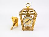 a small gold clock with a key attached to it