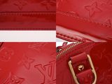 a close up of a red louis vu vu bag with gold hardware
