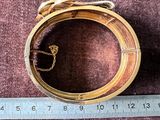 une bague en or munie d'une chaîne, posée à côté d'une règle