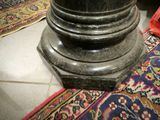 a close up of a black marble pedestal on a rug