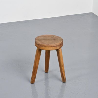 a small wooden stool sitting on top of a cement floor