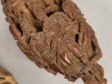 a wooden object with carvings on it next to a pen
