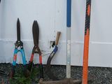 de nombreux outils de jardinage de toutes sortes posés par terre près d'un mur