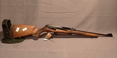 un fusil et une chaussure sont posés sur une table à fond blanc