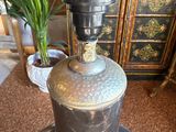 a large metal bell sitting on a table next to a potted plant