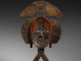un masque en bois posé sur un socle et représentant un visage