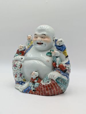 a figurine of a smiling buddha sitting on a pillow