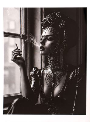 black and white photograph of a woman smoking a cigarette in front of a window