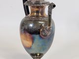 a vase that is sitting on a stand on a white surface