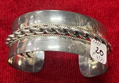 bracelet manchette en argent avec motif tressé et étiquette de prix sur un tissu rouge