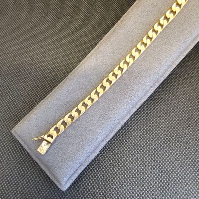 gros plan d'un bracelet en chaîne en or sur une surface grise