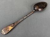 silver spoon with a face on it sitting on a gray surface