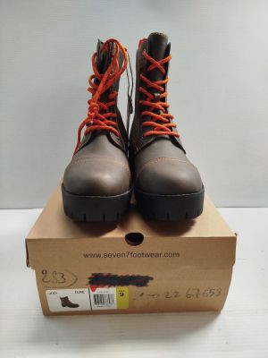 une paire de bottes marron avec des lacets orange posée sur une boîte en carton