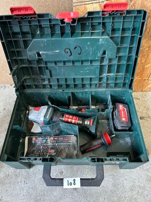une boîte à outils verte posée par terre, contenant des outils