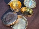 several different types of silver and gold containers sitting on a table