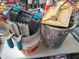 a bucket of tools sitting on a table next to a bucket of paint