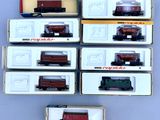 Plusieurs wagons de train miniature sont alignés en rang sur une table