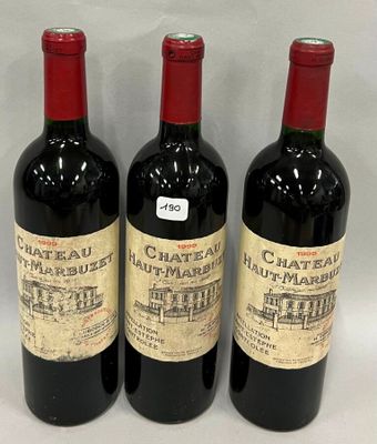 trois bouteilles de vin rouge sont alignées sur une surface blanche