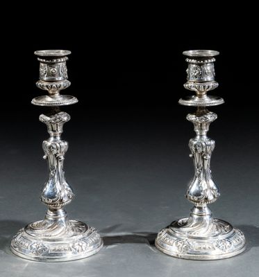 une paire de bougeoirs anciens en argent posés sur une table devant un fond noir