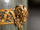 a green vase with a gold decoration on it