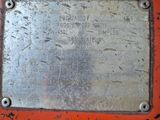 a metal plaque on the side of a rusted red truck