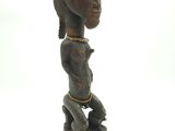 statue d'une femme coiffée d'une coiffe, posée sur un socle en bois