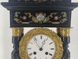 a black and gold clock on a stand with a white background