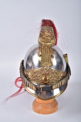 un casque en argent et en or posé sur un socle en bois