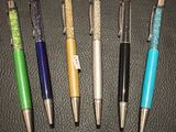 quatre stylos de couleurs différentes alignés sur une surface noire