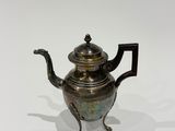a silver tea pot on a stand on a white surface