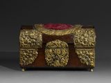 une boîte ancienne en bois ornée de motifs dorés et recouverte d'un tissu rouge