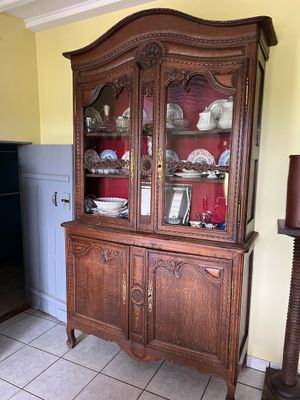 a wooden china cabinet in the corner of the room