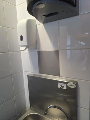 un lavabo équipé d'un distributeur de savon et d'un distributeur de savon fixé au mur
