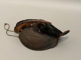a small hat with a feather on it on a white surface