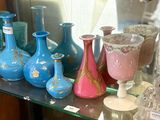 de nombreux vases de différentes couleurs posés sur une étagère en verre