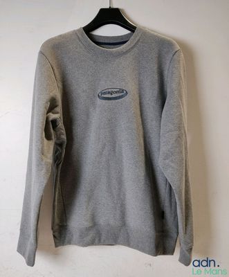 un sweat-shirt gris suspendu à un cintre accroché au mur d'une pièce
