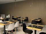 many tables and chairs in this restaurant with a man sitting at the table