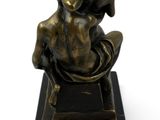 bronze statue of a woman sitting on a black marble base
