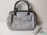 the grey purse is sitting on a white surface with a tag
