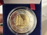 someone is holding a coin in a blue box with a red ribbon