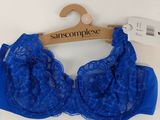 La bralette est bleue et est munie d'un cintre en bois.