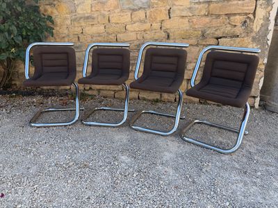 three brown chairs sitting next to each other in front of a brick wall