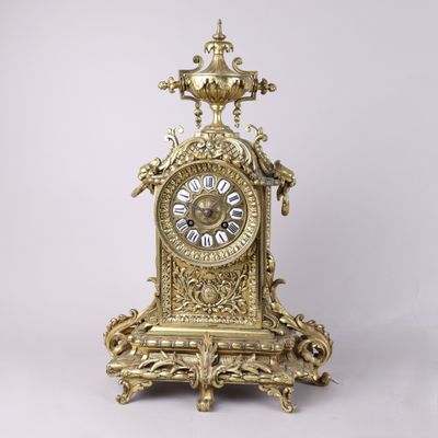 une horloge en or posée sur une surface blanche