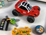 a red toy car with a key, keys, and other toys on a table